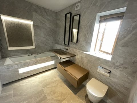 Bath beneath a backlit niche mirror